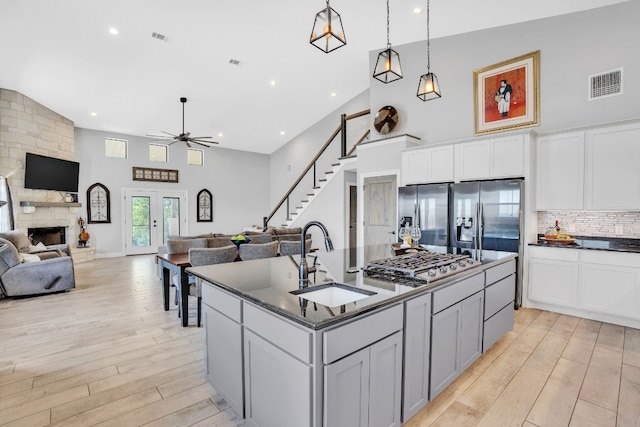 kitchen featuring appliances with stainless steel finishes, light hardwood / wood-style flooring, a fireplace, sink, and a center island with sink