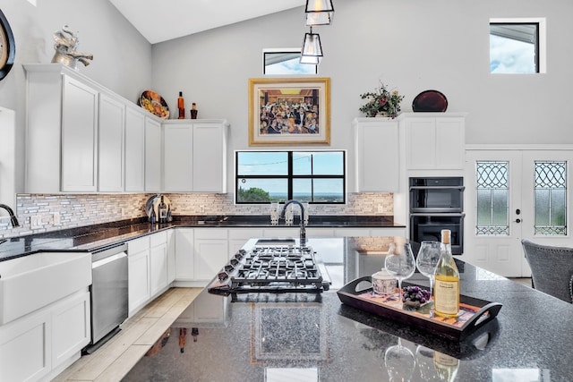 kitchen with white cabinets, backsplash, stainless steel dishwasher, light hardwood / wood-style flooring, and black double oven