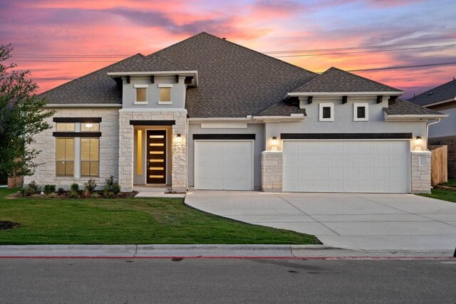 prairie-style home with a garage and a lawn