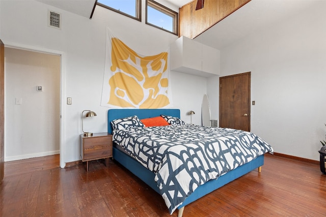 bedroom with dark wood-type flooring and a towering ceiling