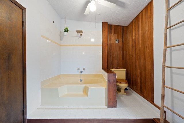 bathroom featuring ceiling fan, toilet, a textured ceiling, tile patterned flooring, and a bath