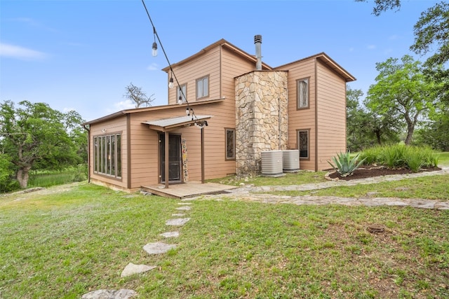 back of house with central AC unit and a lawn