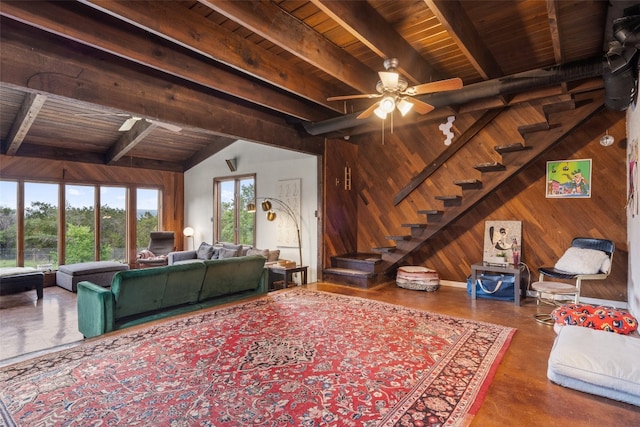 living room with ceiling fan, wooden ceiling, vaulted ceiling with beams, and wooden walls