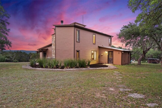 back house at dusk featuring a yard