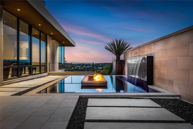 pool at dusk with an outdoor fire pit