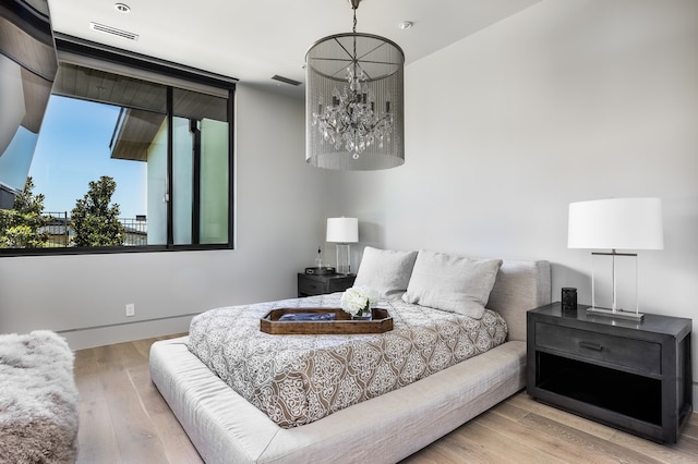 bedroom with light hardwood / wood-style floors and a chandelier