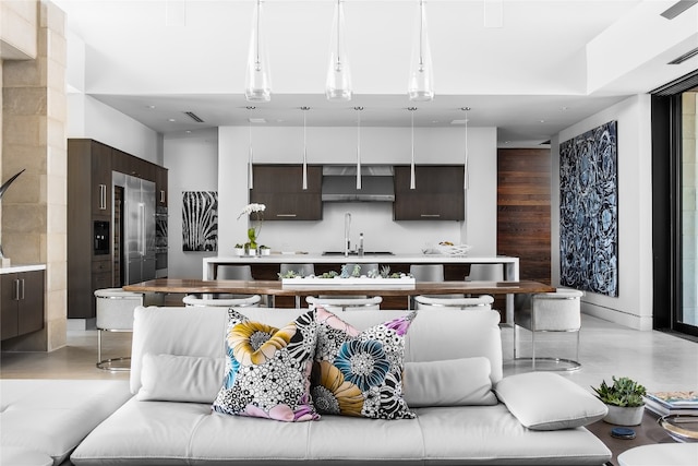 kitchen featuring a high ceiling, sink, pendant lighting, and dark brown cabinets