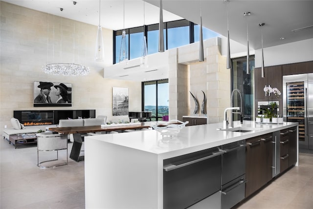 kitchen with decorative light fixtures, a fireplace, sink, and an island with sink