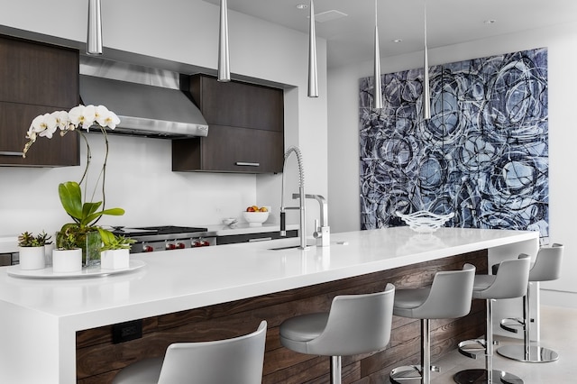 kitchen featuring a kitchen bar, dark brown cabinetry, wall chimney range hood, and range