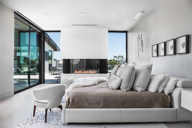 bedroom with access to outside, multiple windows, and a wall of windows