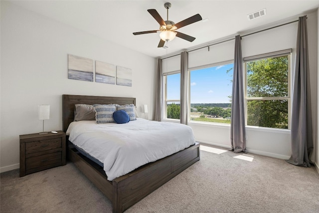 carpeted bedroom featuring a ceiling fan, visible vents, and baseboards