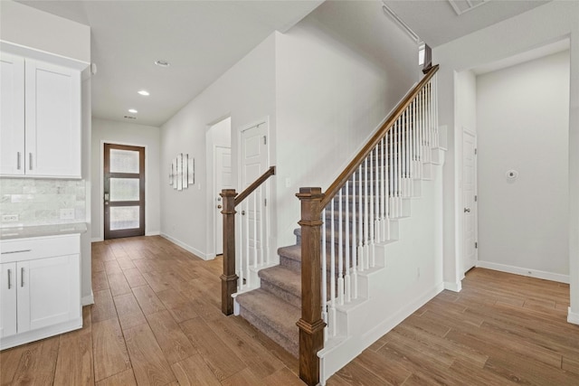 entryway with baseboards, recessed lighting, stairs, and light wood-style floors