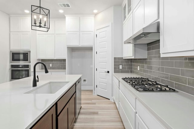 kitchen featuring pendant lighting, sink, stainless steel appliances, white cabinets, and light wood-type flooring