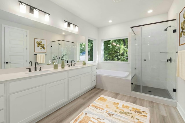 bathroom featuring hardwood / wood-style flooring, plus walk in shower, and vanity