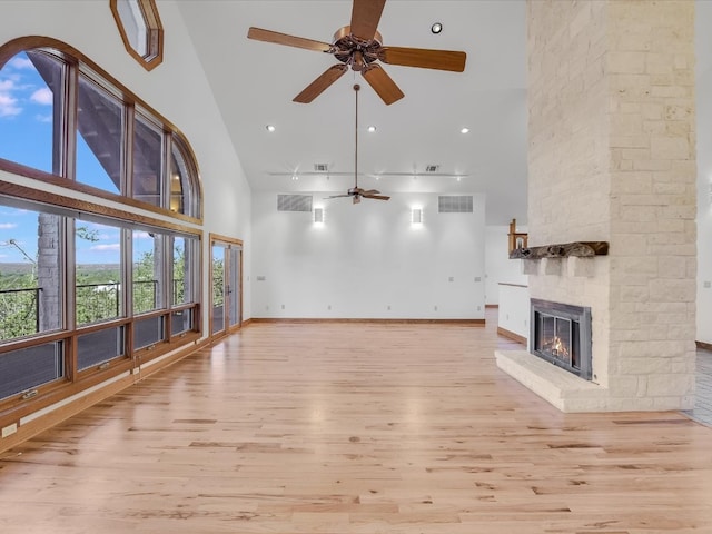 unfurnished living room with ceiling fan, light wood-type flooring, a fireplace, and high vaulted ceiling