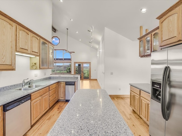 kitchen with sink, high vaulted ceiling, light hardwood / wood-style flooring, appliances with stainless steel finishes, and light stone countertops