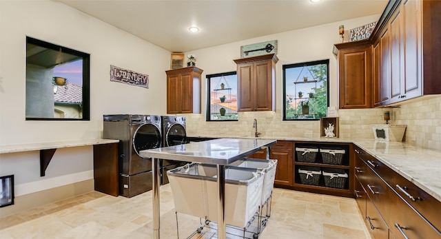 kitchen featuring tasteful backsplash, independent washer and dryer, light tile flooring, light stone counters, and sink