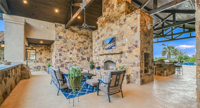 view of patio / terrace featuring an outdoor stone fireplace, an outdoor bar, exterior kitchen, and ceiling fan