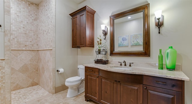 bathroom with a tile shower, toilet, tile floors, and large vanity