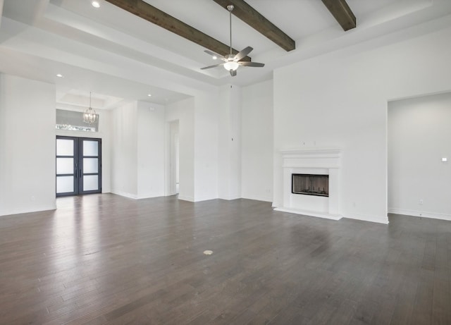 unfurnished living room featuring ceiling fan with notable chandelier, beam ceiling, and dark wood-type flooring