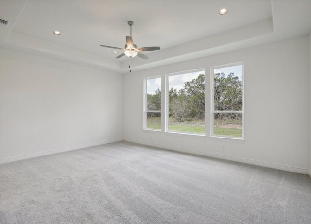 unfurnished room featuring light colored carpet, ceiling fan, and a raised ceiling