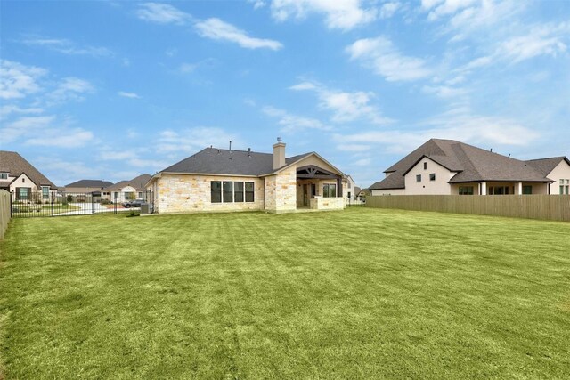 509 Sierra Lisa Cv, Liberty Hill, TX 78642 - back of property with a fenced backyard, a chimney, stone siding, and a residential view
