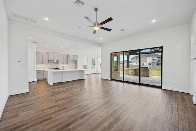 unfurnished living room featuring ceiling fan, sink, and dark hardwood / wood-style floors