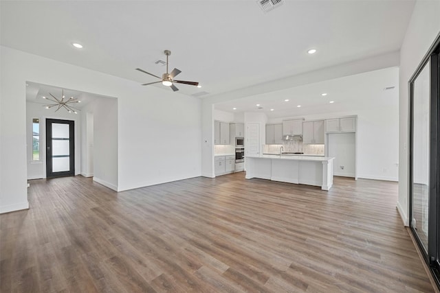 509 Sierra Lisa Cv, Liberty Hill, TX 78642 - unfurnished living room with wood finished floors, recessed lighting, a ceiling fan, and a chandelier