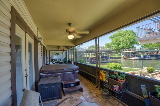 sunroom featuring a water view, ceiling fan, and a healthy amount of sunlight