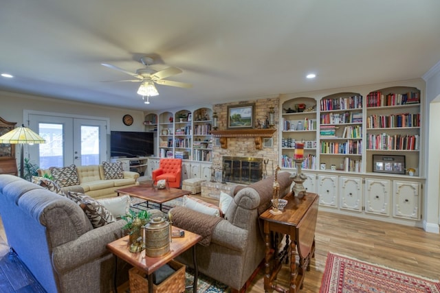 living room with ceiling fan, a large fireplace, crown molding, french doors, and hardwood / wood-style flooring