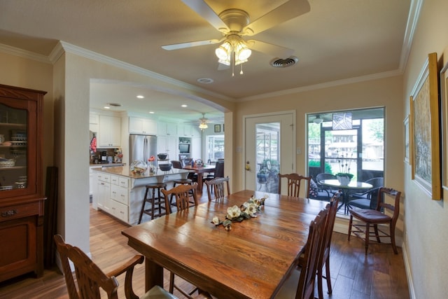 dining room featuring ornamental molding, wood-type flooring, ceiling fan, and a healthy amount of sunlight