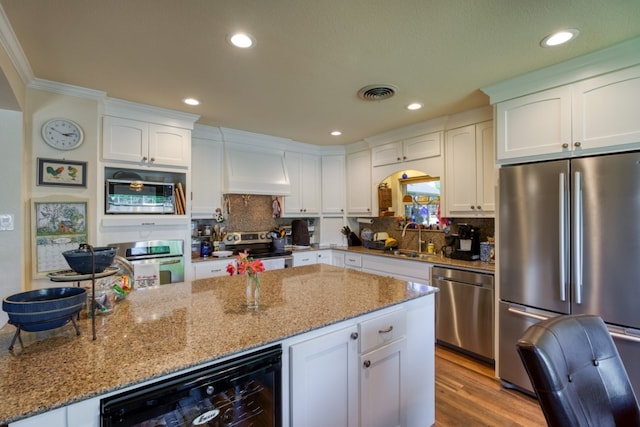 kitchen featuring appliances with stainless steel finishes, tasteful backsplash, white cabinets, and custom range hood