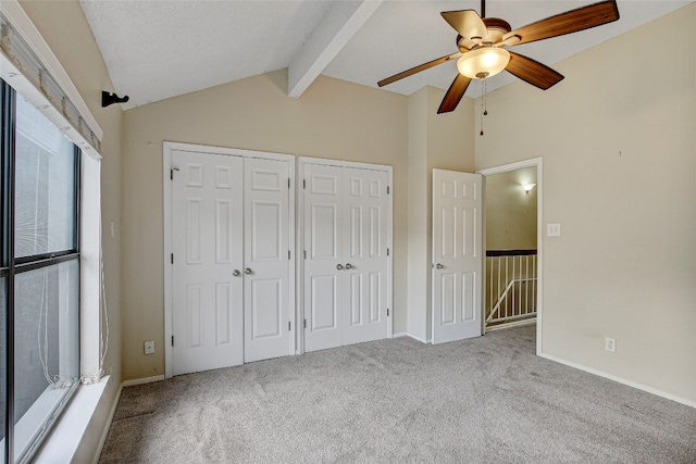 unfurnished bedroom featuring ceiling fan, multiple closets, vaulted ceiling, and carpet flooring