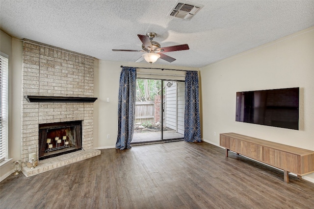 unfurnished living room featuring ornamental molding, dark hardwood / wood-style floors, a textured ceiling, ceiling fan, and a brick fireplace