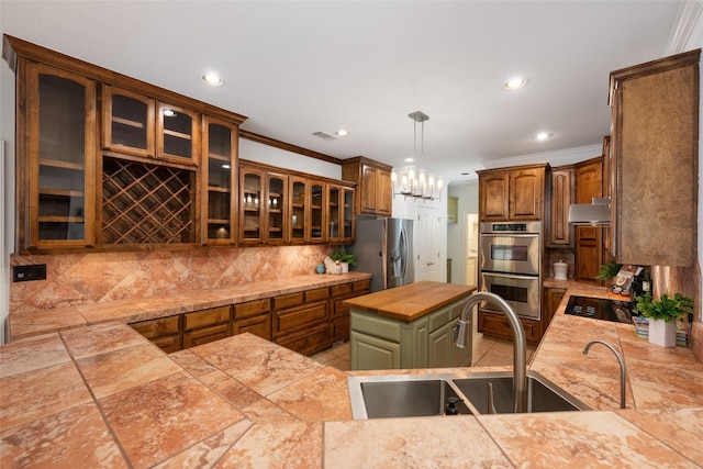 kitchen with appliances with stainless steel finishes, tasteful backsplash, sink, pendant lighting, and a center island