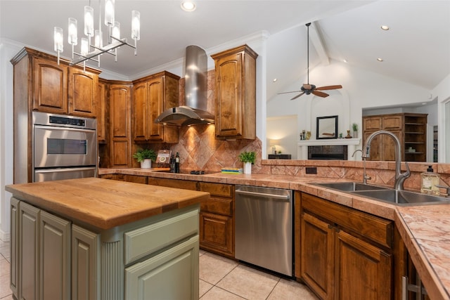 kitchen with decorative light fixtures, appliances with stainless steel finishes, a kitchen island, vaulted ceiling with beams, and wall chimney exhaust hood