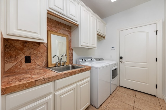 laundry room with cabinets, sink, light tile floors, and washer and dryer