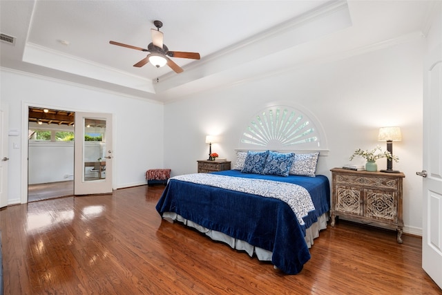 bedroom with ornamental molding, ceiling fan, a tray ceiling, and dark wood-type flooring