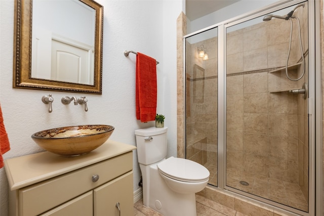 bathroom featuring tile floors, toilet, large vanity, and a shower with shower door