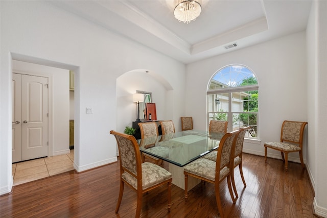 dining space featuring hardwood / wood-style floors, a notable chandelier, and a raised ceiling