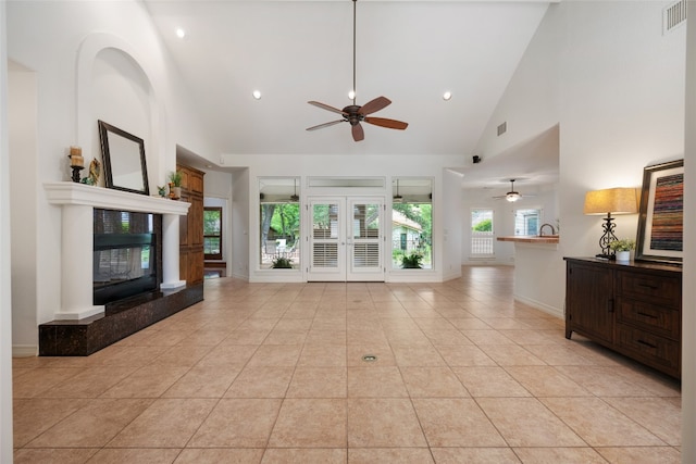 unfurnished living room with a high end fireplace, high vaulted ceiling, ceiling fan, and light tile floors