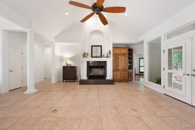 unfurnished living room with a fireplace, ceiling fan, light tile floors, and decorative columns