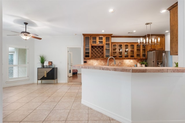 kitchen with stainless steel fridge with ice dispenser, ceiling fan with notable chandelier, tasteful backsplash, pendant lighting, and light tile floors