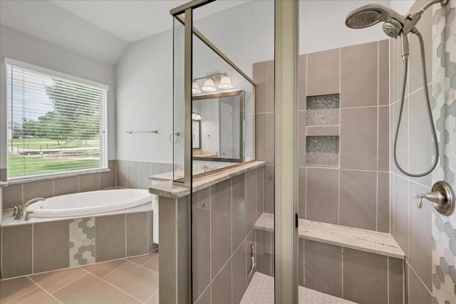 full bathroom with lofted ceiling, tile patterned flooring, a garden tub, and a shower stall