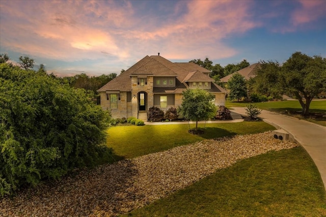 view of front of house featuring stone siding, a lawn, and concrete driveway