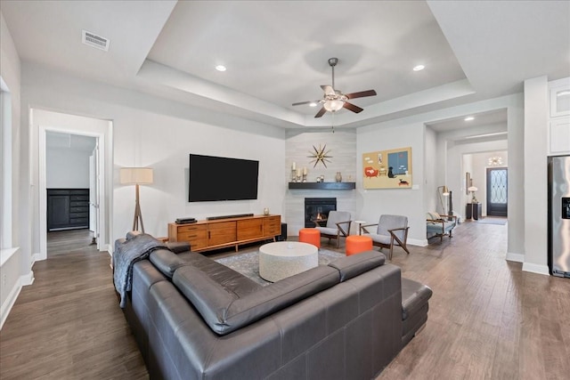 living room with dark wood-style floors, baseboards, a fireplace, and a tray ceiling