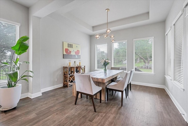 dining area featuring a chandelier, a raised ceiling, baseboards, and dark wood-style flooring