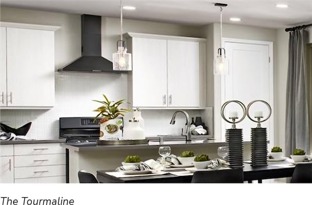 kitchen with wall chimney range hood, white cabinets, decorative backsplash, pendant lighting, and sink