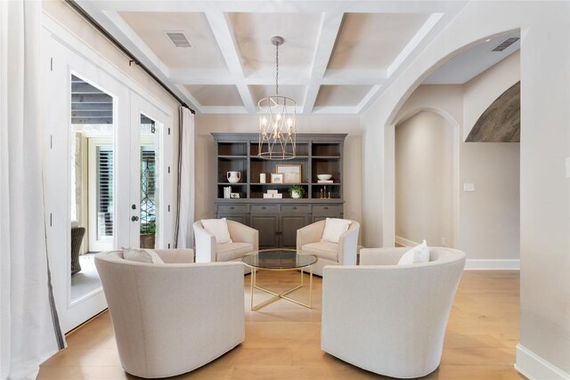 interior space featuring french doors, coffered ceiling, an inviting chandelier, beamed ceiling, and light wood-type flooring