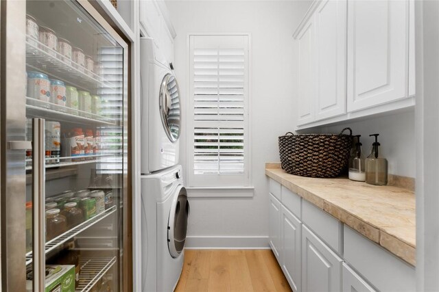 washroom featuring light hardwood / wood-style flooring, cabinets, and stacked washer and clothes dryer